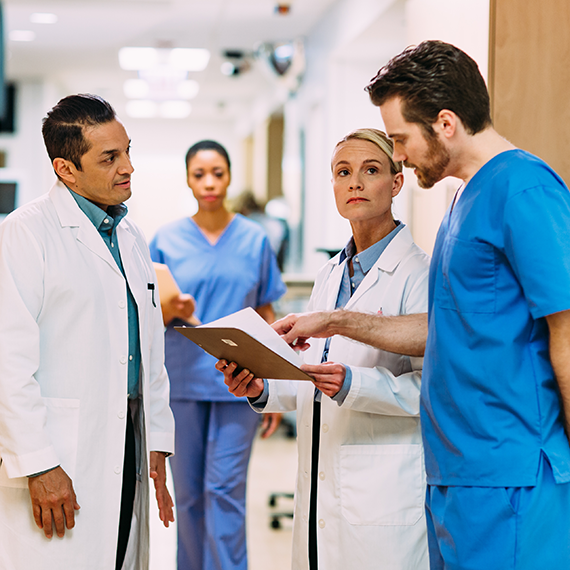 Doctors and nurse gather in hallway to discuss patient chart