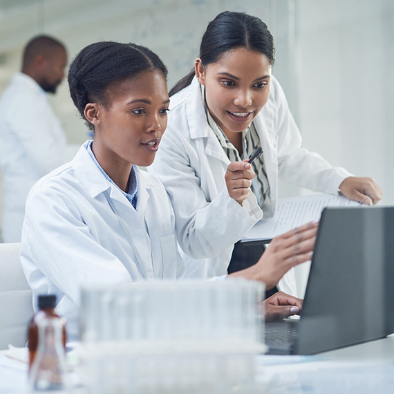 Women in lab coats looking at screen